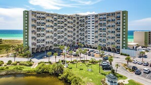 A high-rise hotel with multiple balconies, a parking lot, and a view of the ocean. - Summer & Fall Beachfront at PP A-301 (Panama City Beach)