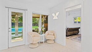 A modern living room with two beige armchairs, a small white table, and a leather sofa. - Tropical 4BR Villa with Pool, BBQ & Mini Golf Fun (Miami)