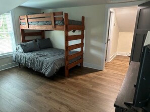 Ein Zimmer mit Etagenbett, Holzboden, einer Tür und einem Fernseher.