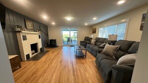 Un salon avec une cheminée, un ensemble de canapés et un plancher en bois.