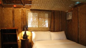 Una stanza in legno con un letto, una lampada e una mensola.