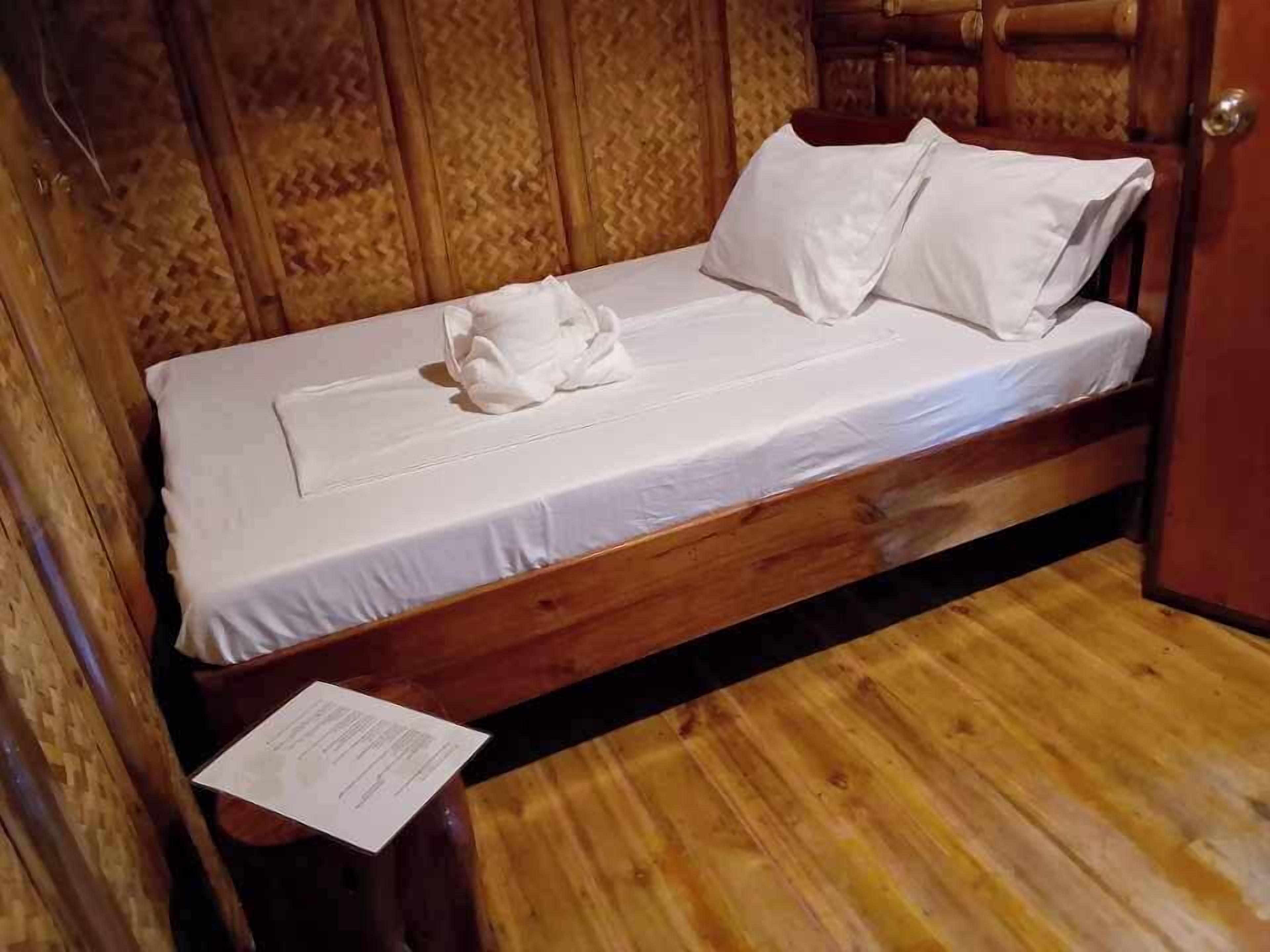 A wooden bed with white linens and pillows, a wooden floor, and a door with a wooden panel design.