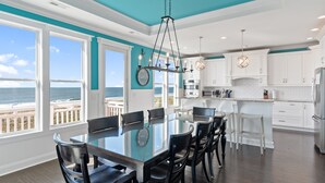 A modern kitchen with white cabinets, a large island, and a view of the ocean. - "Coral Relief" 6 Bedroom, 6.5 Bathrooms, Private Pool and Elevator! (Supply)