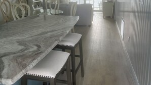 Una cucina moderna con un piano di lavoro in marmo, sedie in legno e una ventola a soffitto.