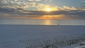 Una spiaggia al tramonto, con cielo sereno e alcune persone in lontananza.