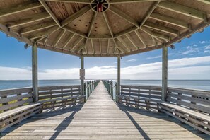 A wooden pier leading to a covered area with a clear view of the sea.