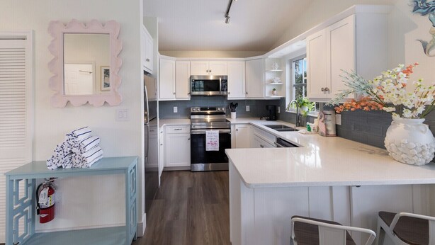A modern kitchen with white cabinets, stainless steel appliances, and a central island.