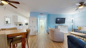 Ein modernes Wohnzimmer mit Essbereich, Küche und einem an der Wand befestigten Fernseher.