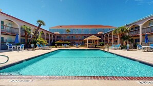 Ein Hotelpoolbereich mit klarem, blauem Pool, Liegestühlen und einer überdachten Sitzgelegenheit.