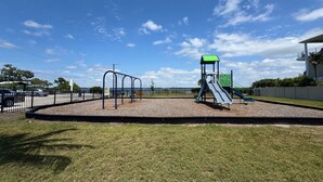 Un parque infantil con tobogán, columpios y una estructura para escalar.