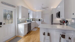 Una cocina moderna con armarios blancos, horno empotrado y refrigerador de acero inoxidable.