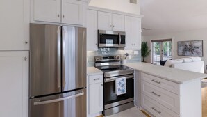 Una cocina moderna con electrodomésticos de acero inoxidable, armarios blancos y una isla grande con encimera.