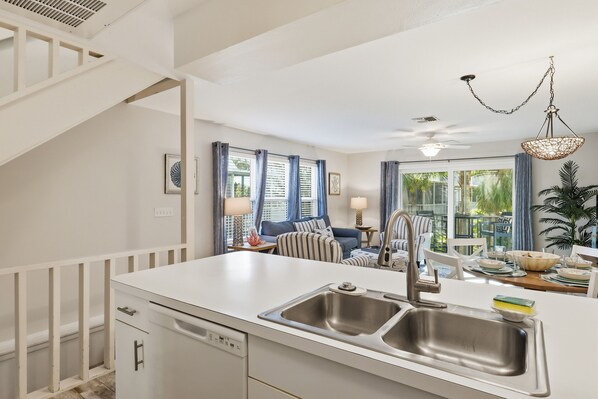 Una cocina moderna con un lavamanos doble, armarios blancos y una zona de comedor con mesa y sillas.