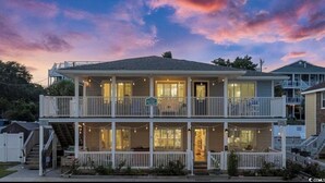A two-story house with a balcony, a porch with string lights, and a sign that reads "doral palm". - The High Tide Hideaway @ The Beach  (North Myrtle Beach)