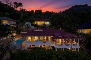 Un resort de varios pisos con piscina, rodeado de exuberante follaje y palmeras.