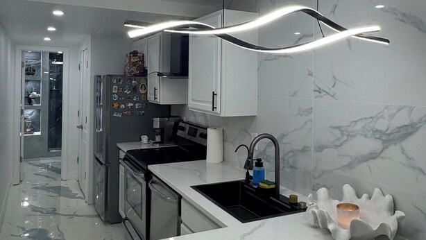 Una cocina moderna con encimera de mármol, electrodomésticos de acero inoxidable y una lámpara colgante original.