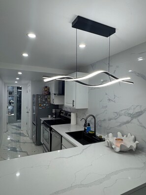 Uma cozinha moderna com bancada de mármore, eletrodomésticos de aço inoxidável e um pendente de design exclusivo.