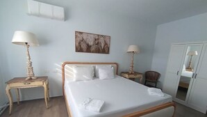 A neatly arranged bedroom with a bed, bedside tables, a chair, a wardrobe, and a wall-mounted artwork. - Tracadero Lodge A1, 1 Bedroom (Dominicus)