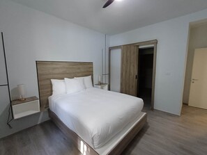 Une chambre à coucher moderne avec une tête de lit en bois, un lit simple, une table de chevet avec une lampe et une armoire.