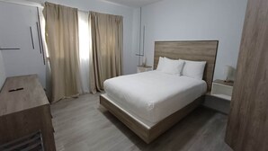 A bedroom with a large bed, a desk, and a wardrobe. - Tracadero Lodge G3 Apt, 2 Bedroom (Dominicus)