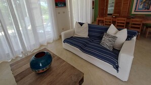 A living room with a sofa, a coffee table, and a dining area with chairs and a table. - Tracadero Marina 26 Apt, 3 Hab. (Dominicus)