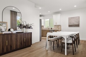 A modern kitchen with white cabinets, a dining table with chairs, and a large mirror above the counter. - New! Cozy Cottage in Spokane Valley (Spokane Valley)