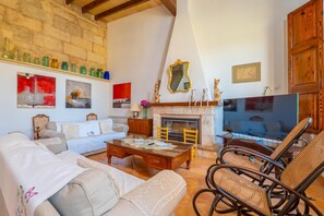 A living room with a fireplace, sofas, a coffee table, wicker chairs, and a TV.