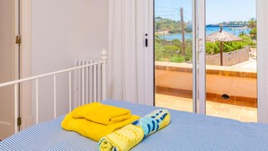 A bedroom with a bed, a window, and a view of a coastal area. - S'ALGUERET - Cozy house with shared pool and sea views in Portopetro - Free Wi-Fi (Santanyí)
