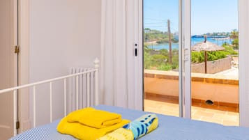 Een slaapkamer met een bed, een raam en uitzicht op de kust.