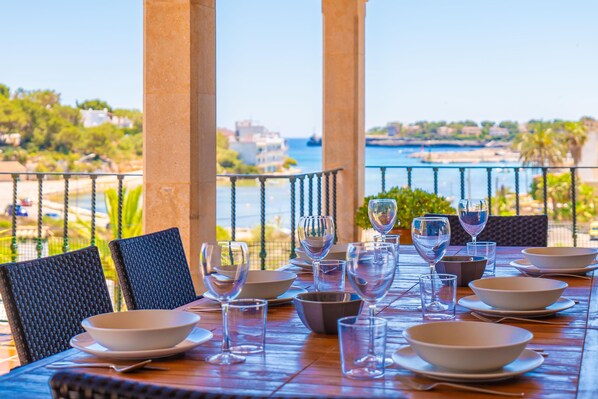 A table set for dining with a view of the sea and buildings in the background.