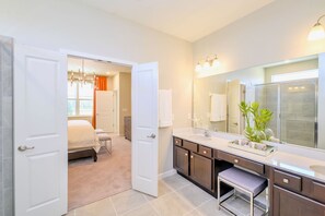 A modern bathroom with a large mirror, a sink, and a shower. - Upstay - 32 Guest Home - Pool Hot Tub and Games (Kissimmee)