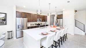 A modern kitchen with stainless steel appliances, a large island, and pendant lighting.