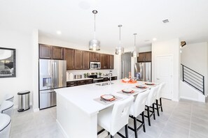 A modern kitchen with stainless steel appliances, a large island, and pendant lighting.