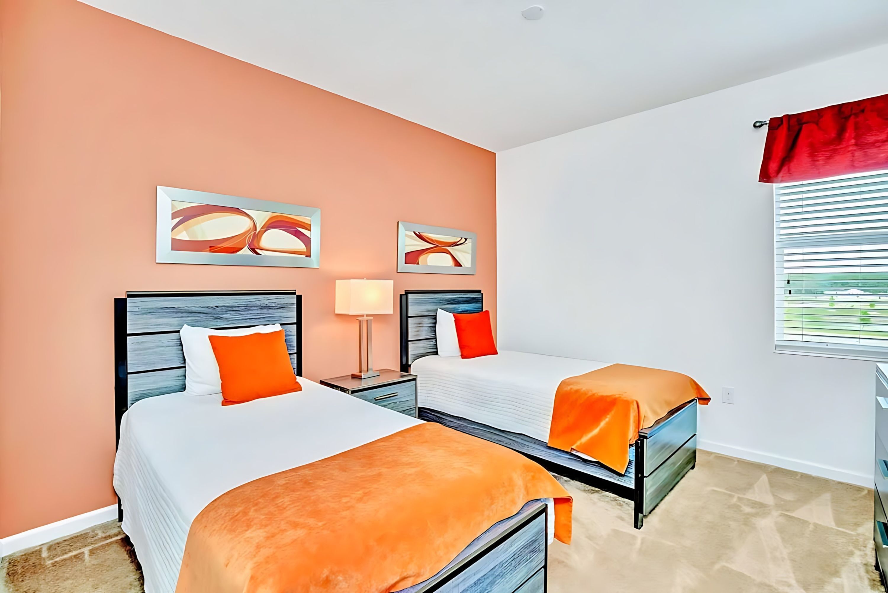 A hotel room with two beds, a nightstand with a lamp, and artwork on the walls.