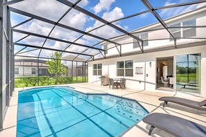 A swimming pool with a glass enclosure, a patio area with outdoor furniture, and a view of a residential building. - Upstay Lakefront Home w Pool Cinema Games BBQ (Kissimmee)