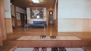 A hallway with wooden flooring, a bench, and a pair of shoes on the floor. - Suzukagojo (Nagahama)