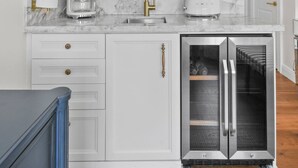 A kitchen with white cabinets, a marble countertop, a coffee maker, a toaster, and a refrigerator. - Condo Studio/Pool/StepsTO Beach/DINE (Palm Beach)