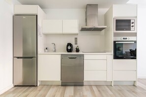 A modern kitchen with stainless steel appliances, white cabinetry, and a dishwasher.