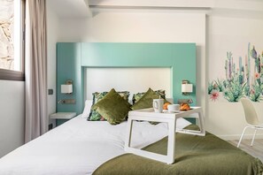 Una habitación de hotel moderna con cama, mesita de noche, una silla y un mural en la pared.