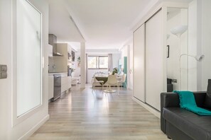 A modern apartment with a kitchen, dining area, and a living room with a sofa and a lamp.