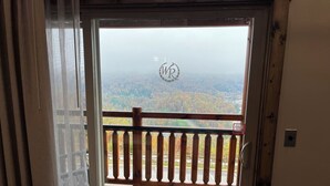 A wooden balcony with a view of a forested landscape.