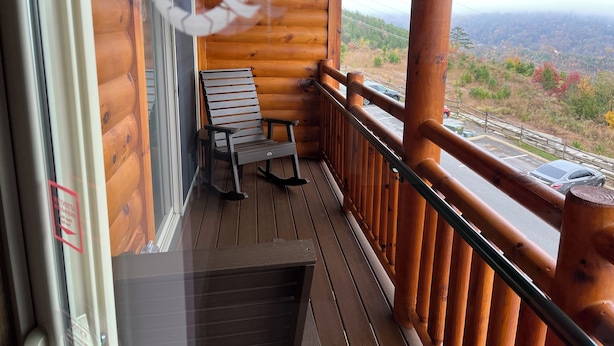 A wooden balcony with a view of a mountainous landscape.