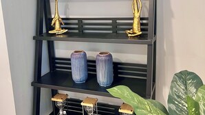 A black metal shelf unit with three levels, each holding decorative items and potted plants.