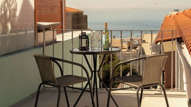 Un balcone con tavolo e sedie, affacciato su uno specchio d'acqua.
