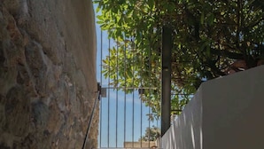 Una scala in cemento con corrimano in metallo, affiancata da muri in pietra e da una parete bianca, che conduce verso un cielo sereno.