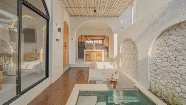 Un interno moderno con una parete in pietra, un pavimento in legno, una piscina e un angolo cottura.