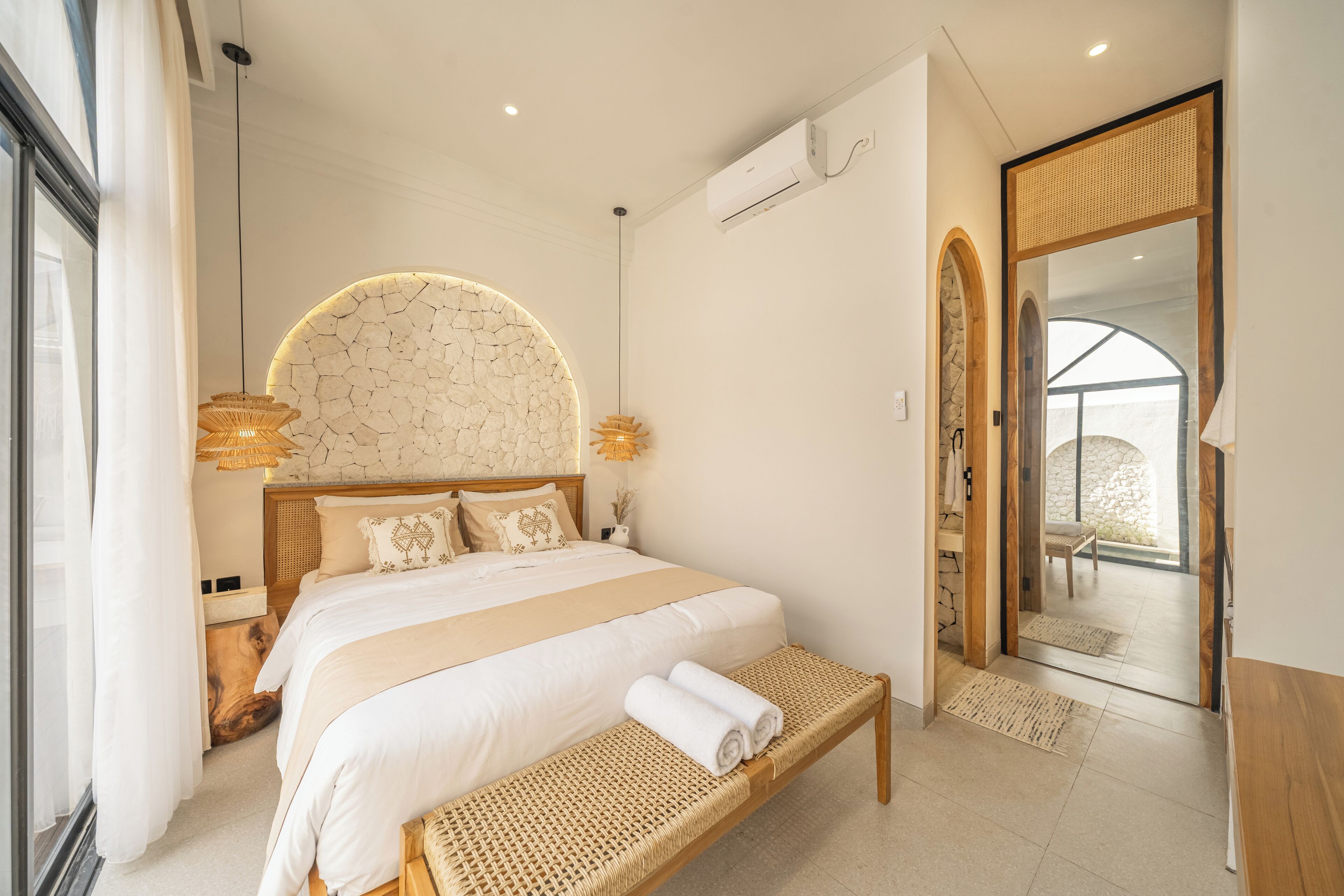 Un dormitorio moderno con una cama grande, un banco y vistas al exterior.