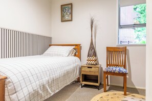 Une chambre à coucher comprenant un lit, une table de chevet, une chaise et une fenêtre donnant sur un paysage verdoyant.
