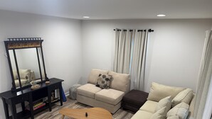 A living room with a sofa, a coffee table, a side table, a mirror, and a window with curtains. - Cozy 3-bedroom house with AC in charming Waxhaw (Waxhaw)