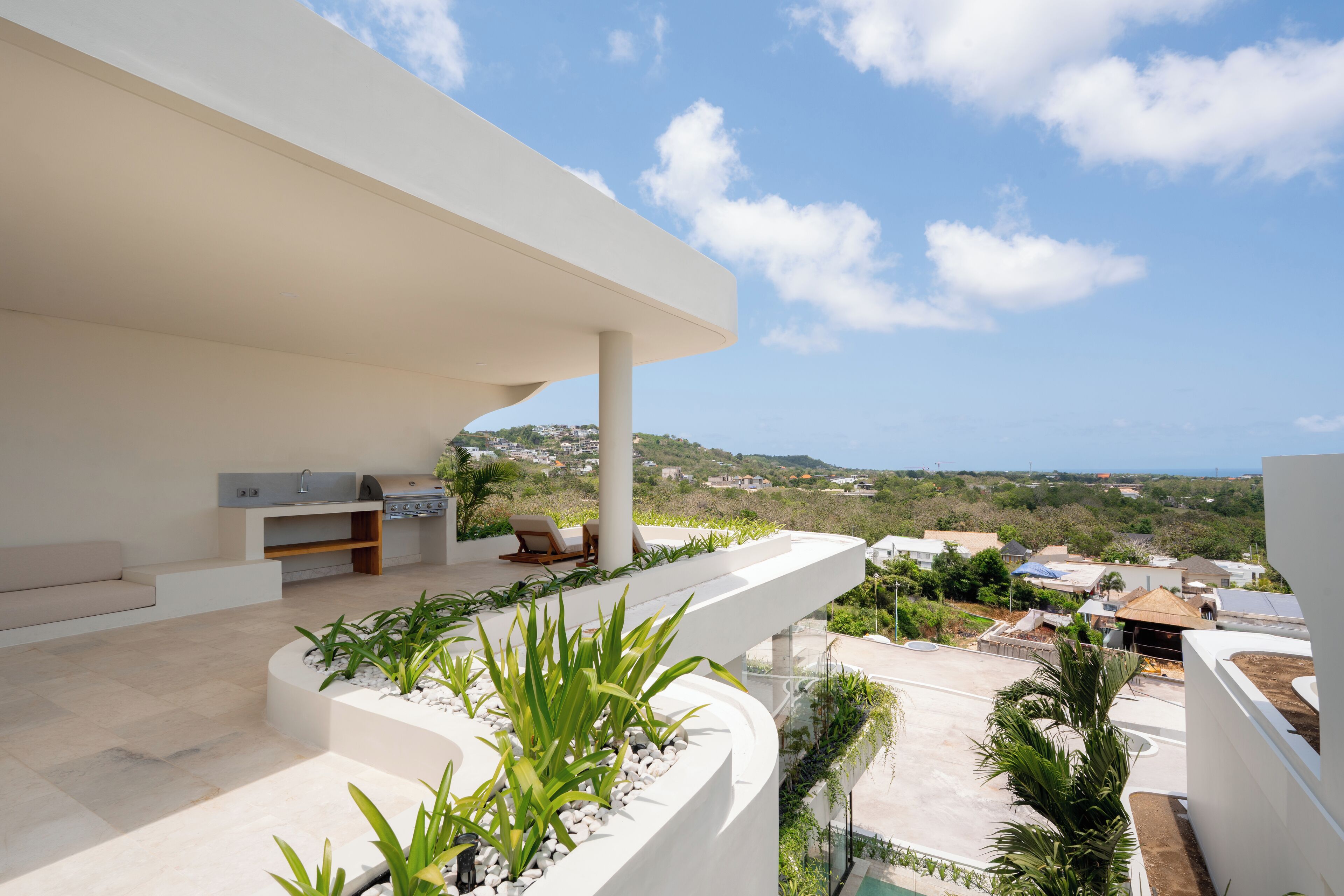 A modern outdoor living area with a pool, seating, and a view of the landscape.